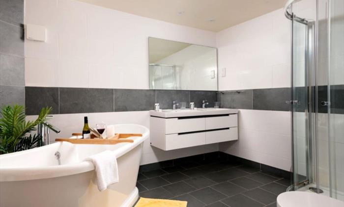 A spacious bathroom with a double sink, shower and bath
